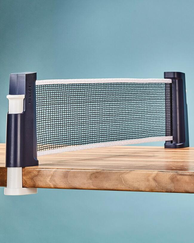 Tischtennisnetz Rollent auf einem Holztisch gespannt, blauer Hintergrund