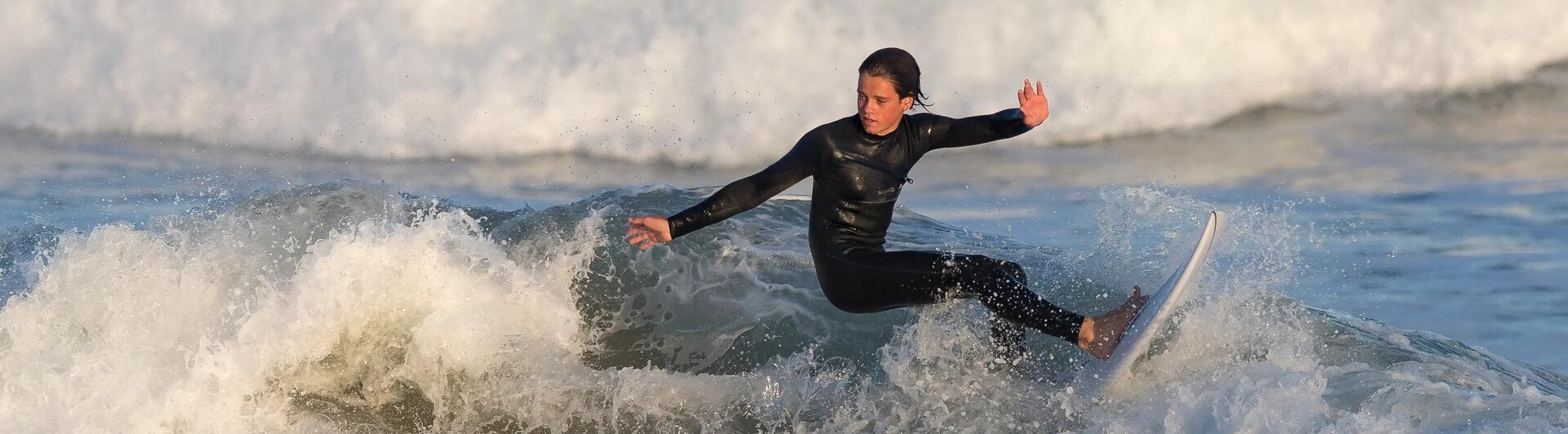 jongen in een wetsuit pakt een golf