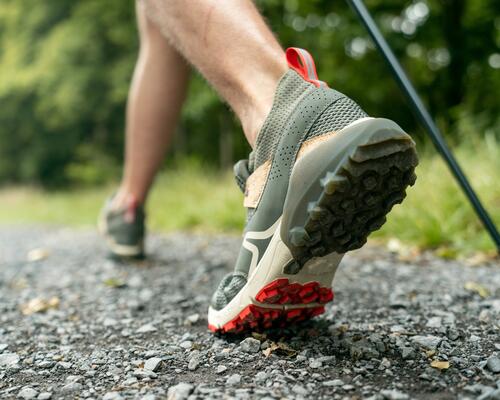 mężczyzna idący z kijkami w butach do nordic walkingu 