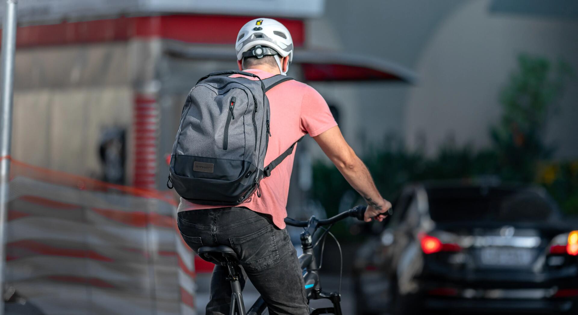 mężczyzna jadący na rowerze w kasku z plecakiem na plecach