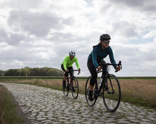 Two people riding bike on bricked path wearing Long-Sleeved Cycling Jersey