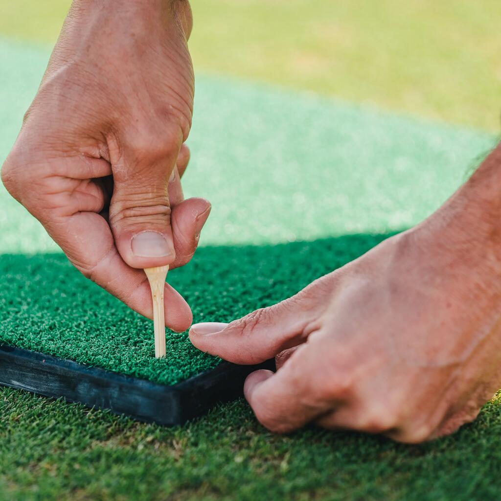 Eine Männerhand die einen Golf-Tee in das Gras steckt.