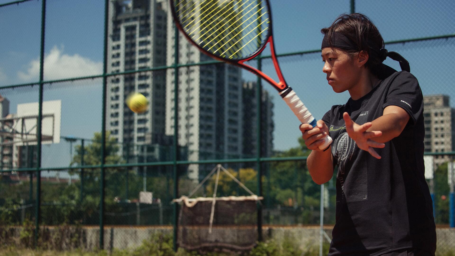 Bild einer Frau, die auf einem Outdoor-Tennisfeld Tennis spielt