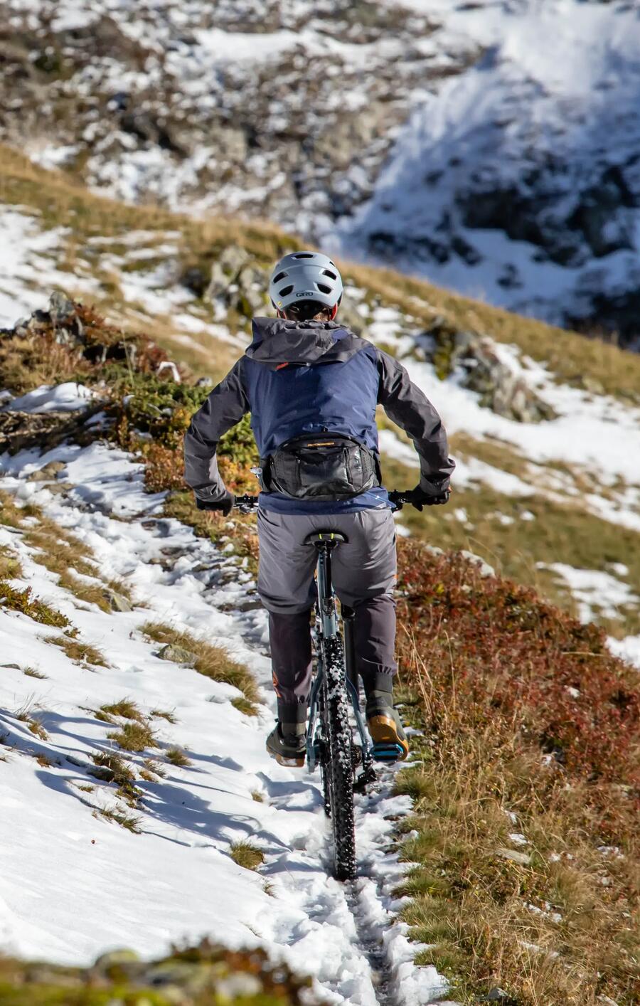Mann fährt einen schneebedeckten Berg herunter mit seinem Mountainbike
