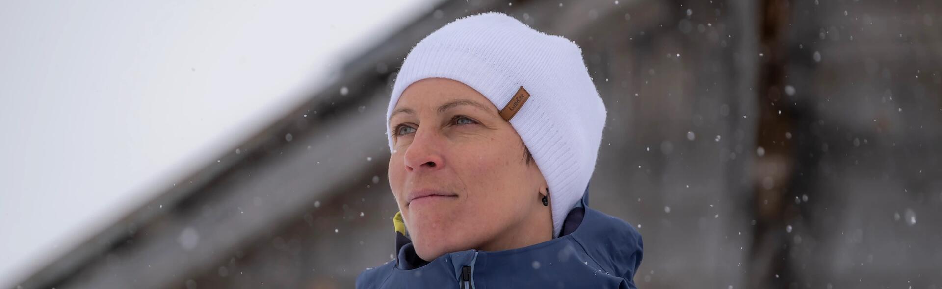 A woman wearing a hat in the snow to keep warm