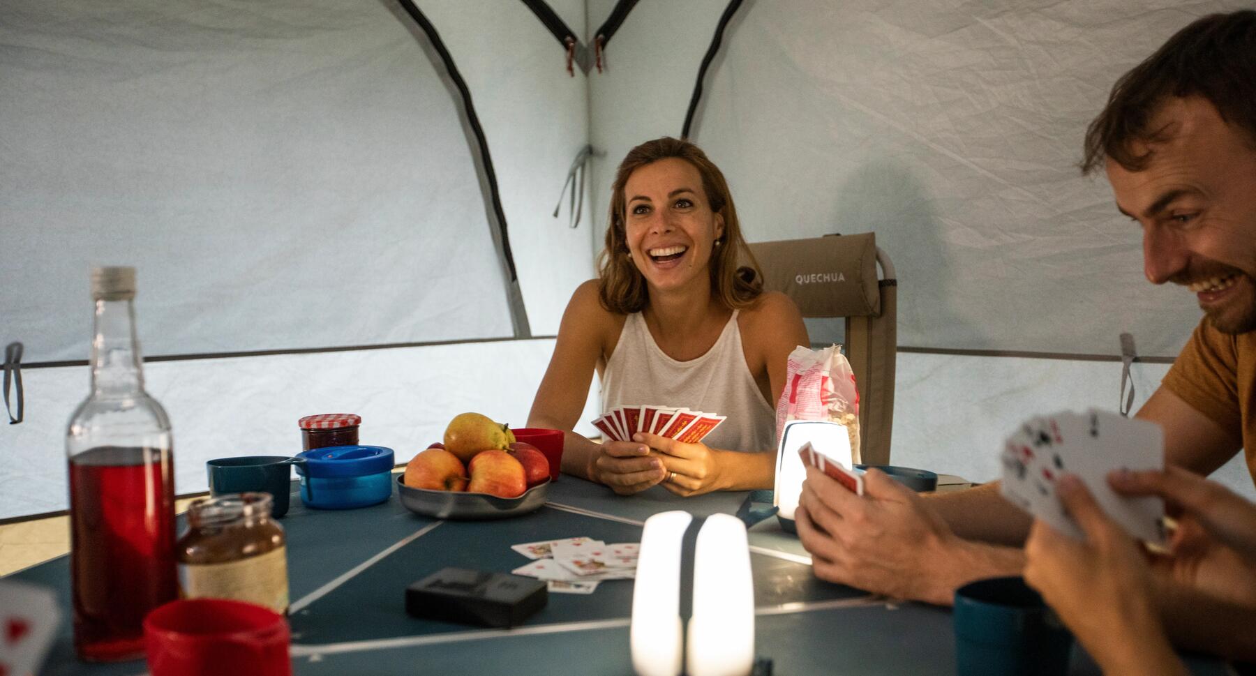 Kartenspiel im Zelt mithilfe eines Campinglichts