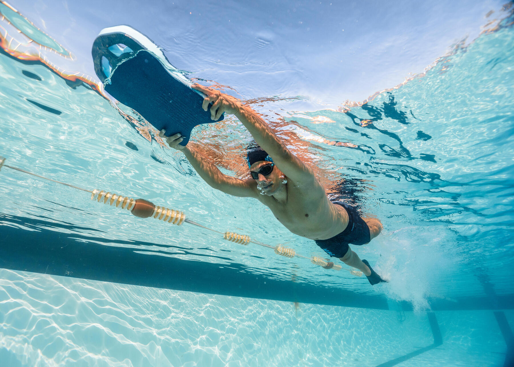 nageur qui s'entraine avec une planche pour améliorer ses battements d ejambes