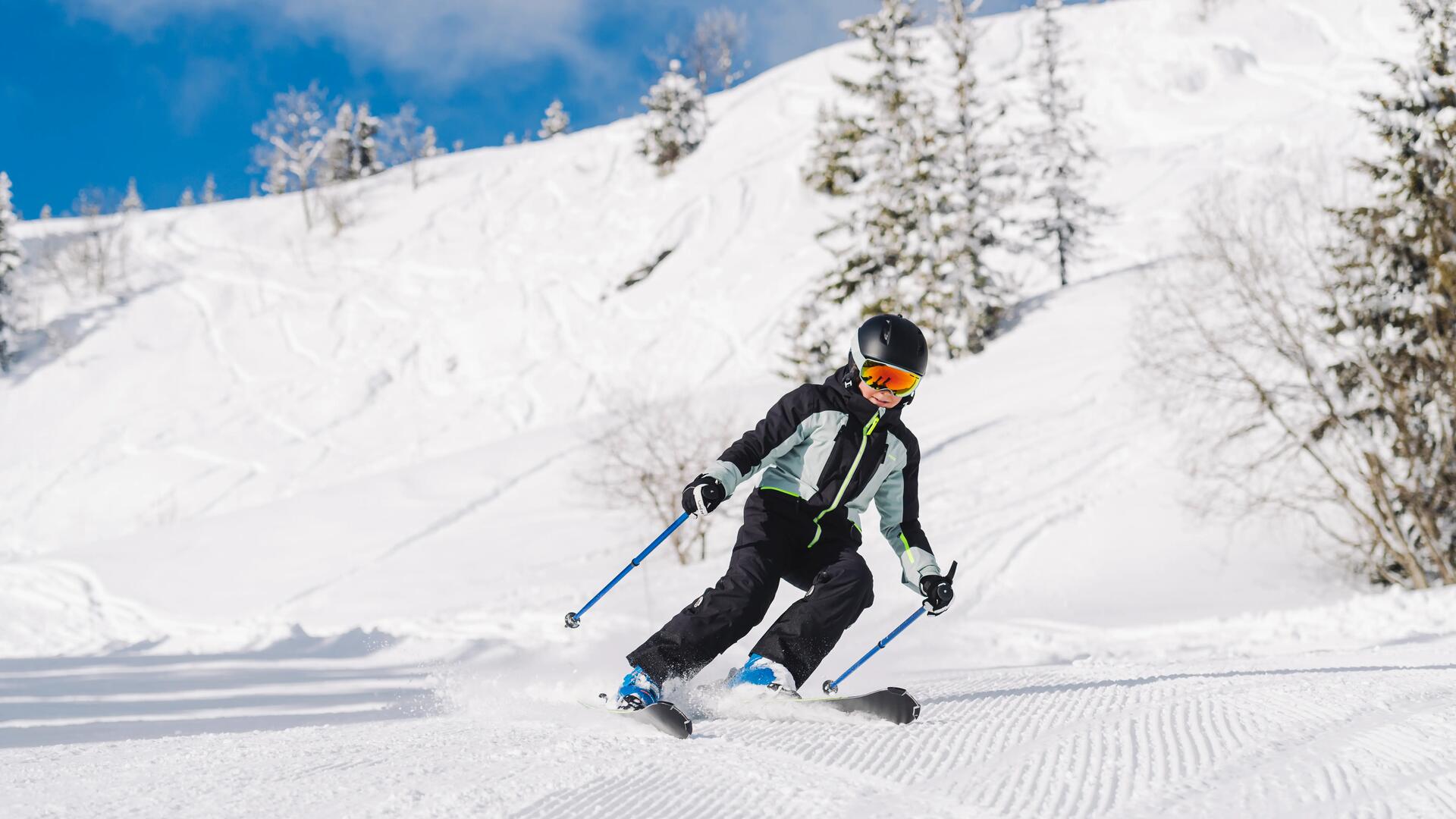 Kind fährt einen Berg auf Skiern herunter