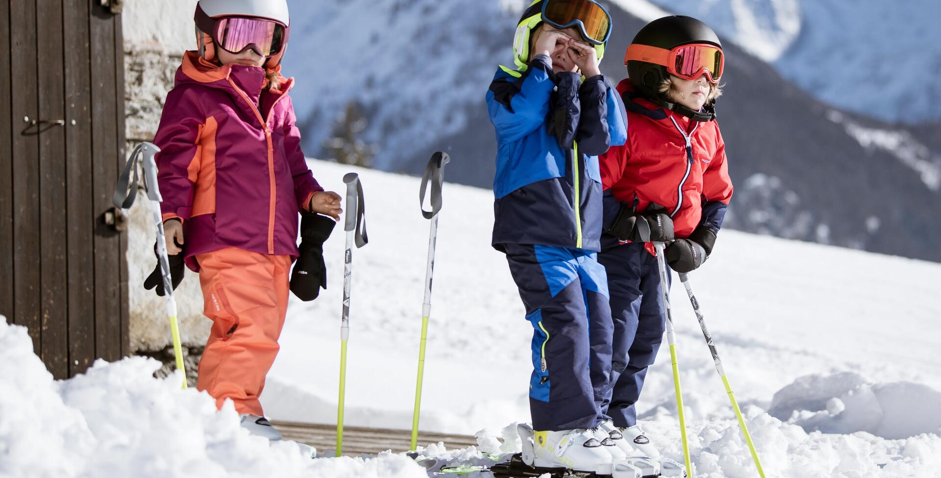 3 kids on their skis preparing to go down the slope