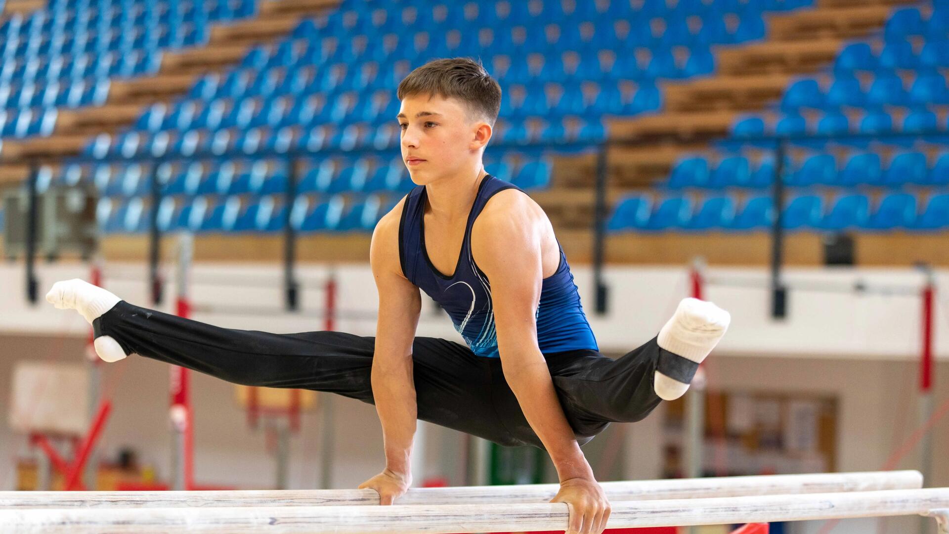chłopiec w odzieży gimnastycznej wykonujący ćwiczenia na drążkach treningowych 