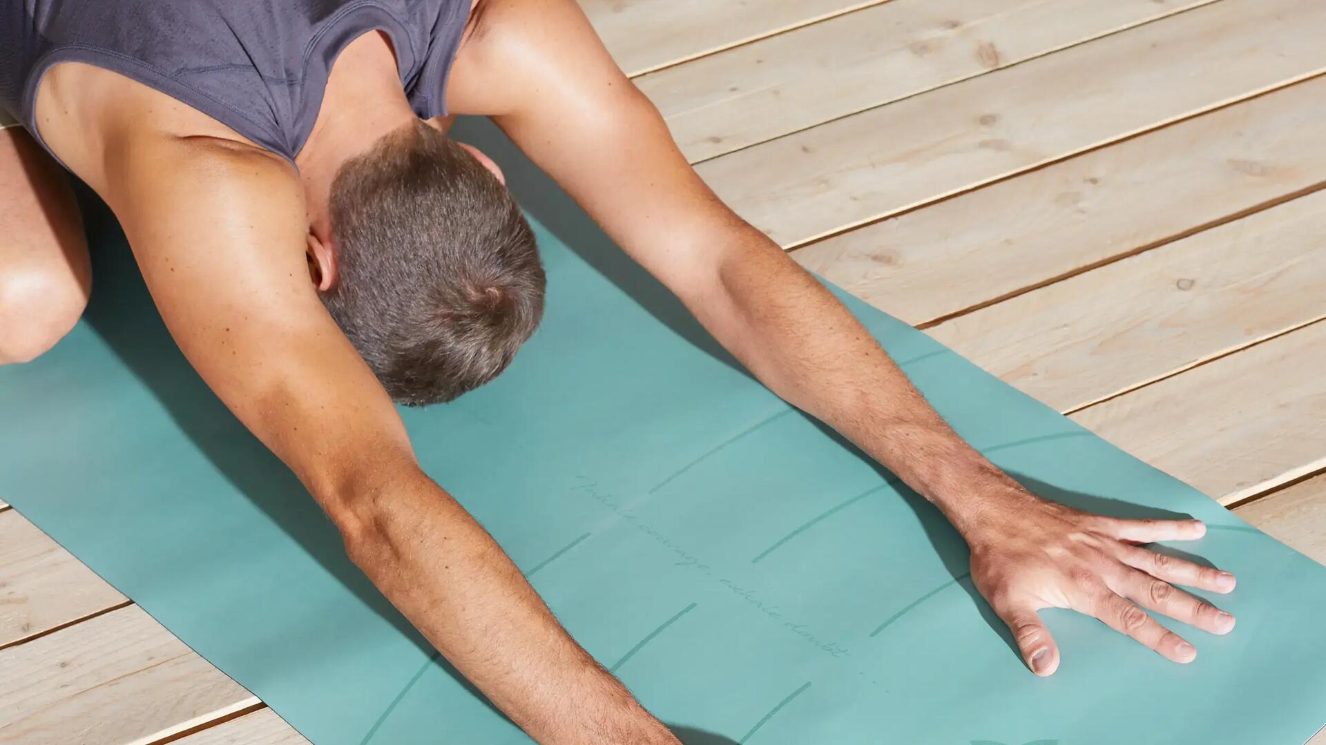 Bild von einem Mann, der auf einer Matte Yoga macht und in der Kind-Position ist