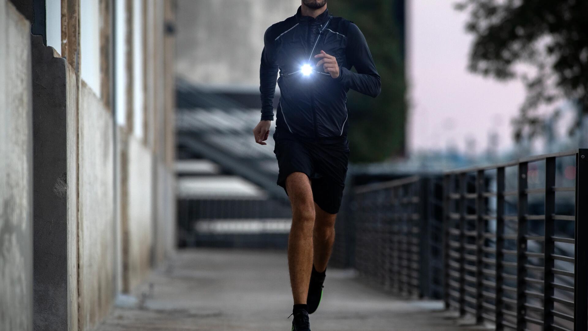 mężczyzna biegnący w butach i odzieży biegowej z latarką do biegania