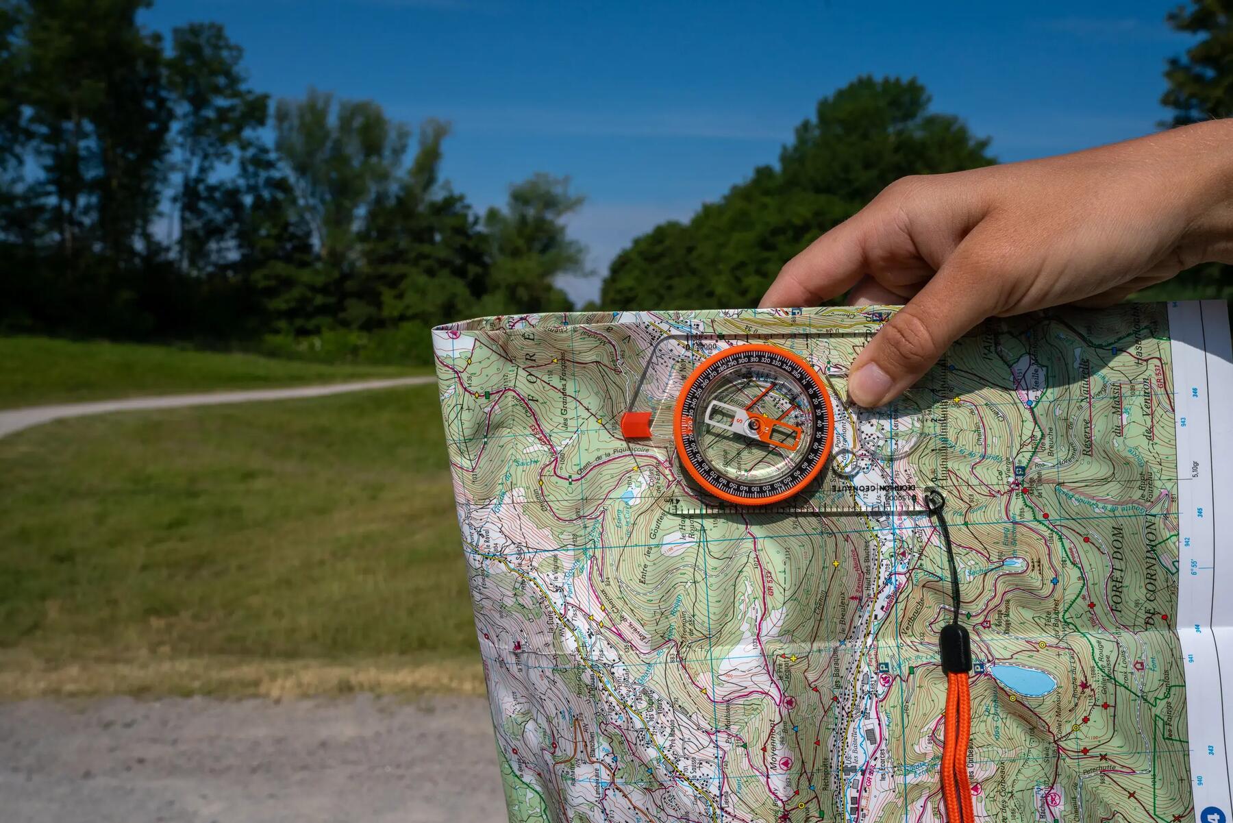 Piechur trzymający mapę z kompasem w górach szukający swojego szlaku