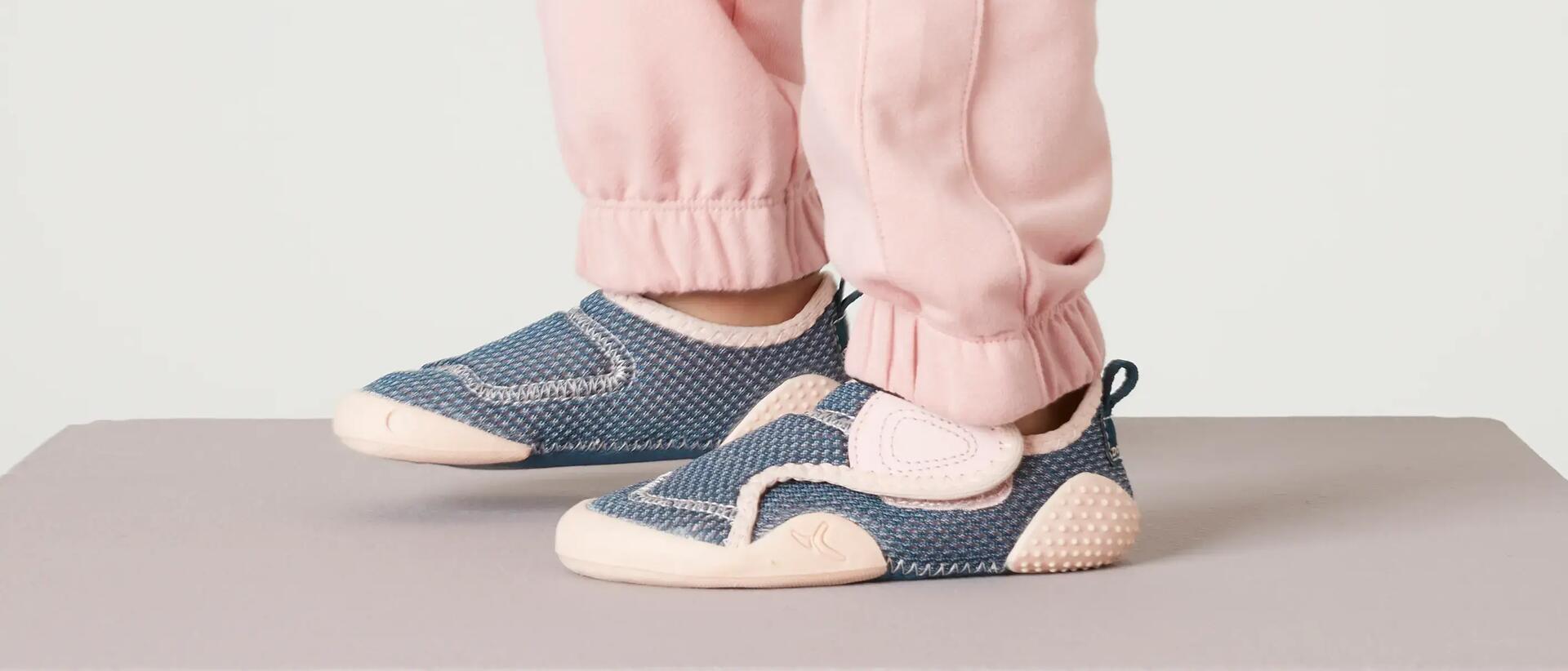 Pés de menina, calça de fato de treino cor-de-rosa e sapatilhas cor-de-rosa e azul