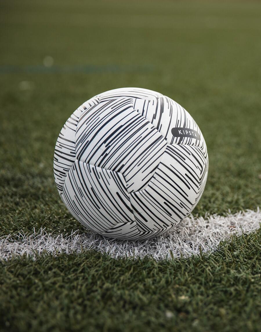 Mann hält einen Fußball der Marke Kipsta in beiden Händen