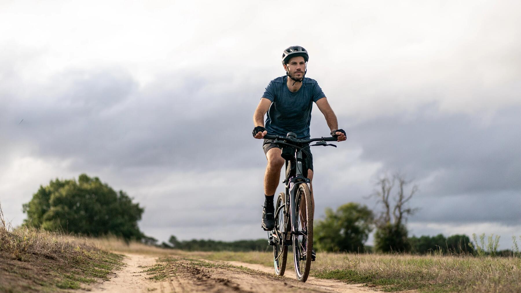 Mężczyzna w kasku i rękawiczkach rowerowych jadący na rowerze