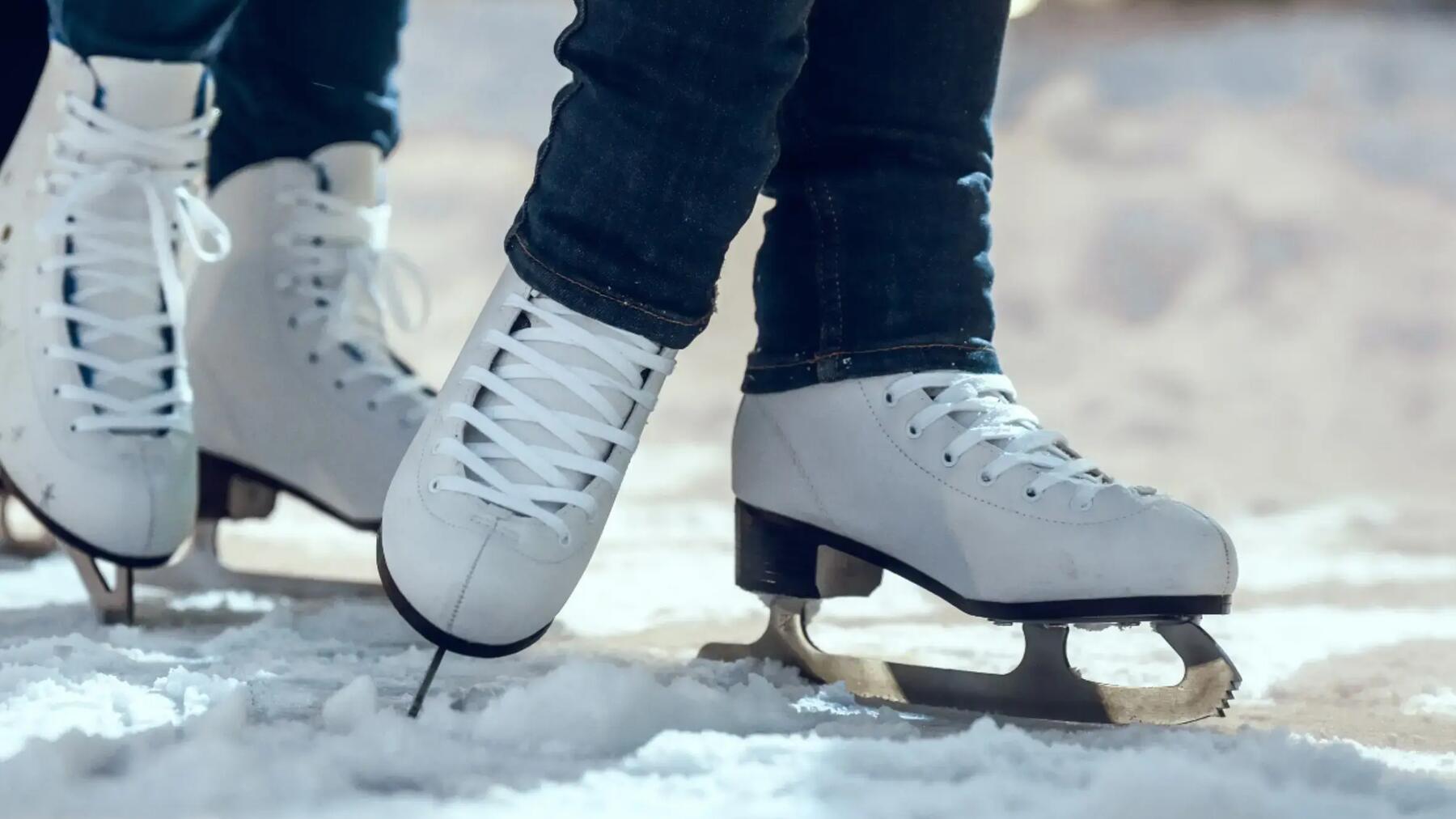 Zwei Menschen tragen weiße Eiskunstlauf-Schlittschuhe