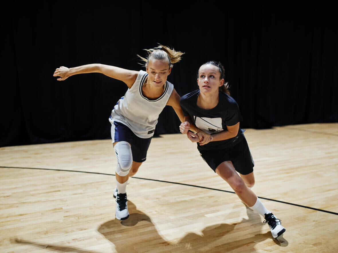 two women wrestling while running on the basketball court