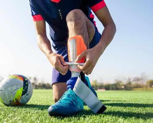 Man adjusting football shin pad on pitch