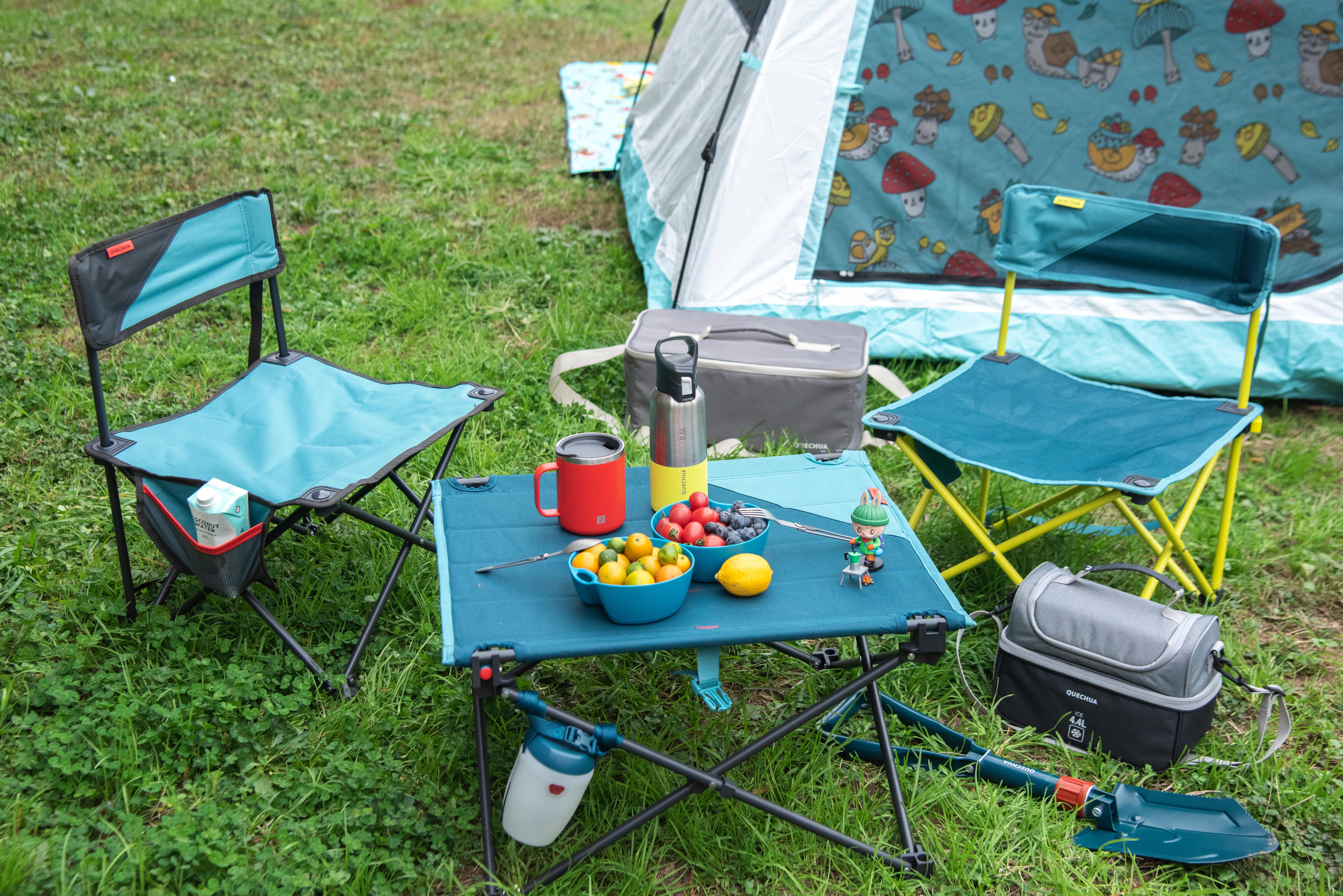 Portable picnic table with snacks and drinks beside a family camping tent