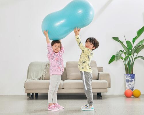dzieci w odzieży sportowej unoszące piłkę gimnastyczną
