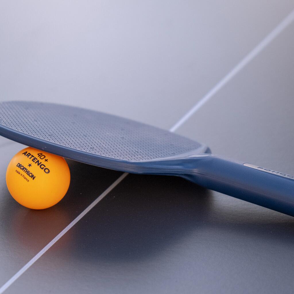 Ein Tischtennisschläger und ein Tischtennisball liegen auf einem Tischtennistisch.