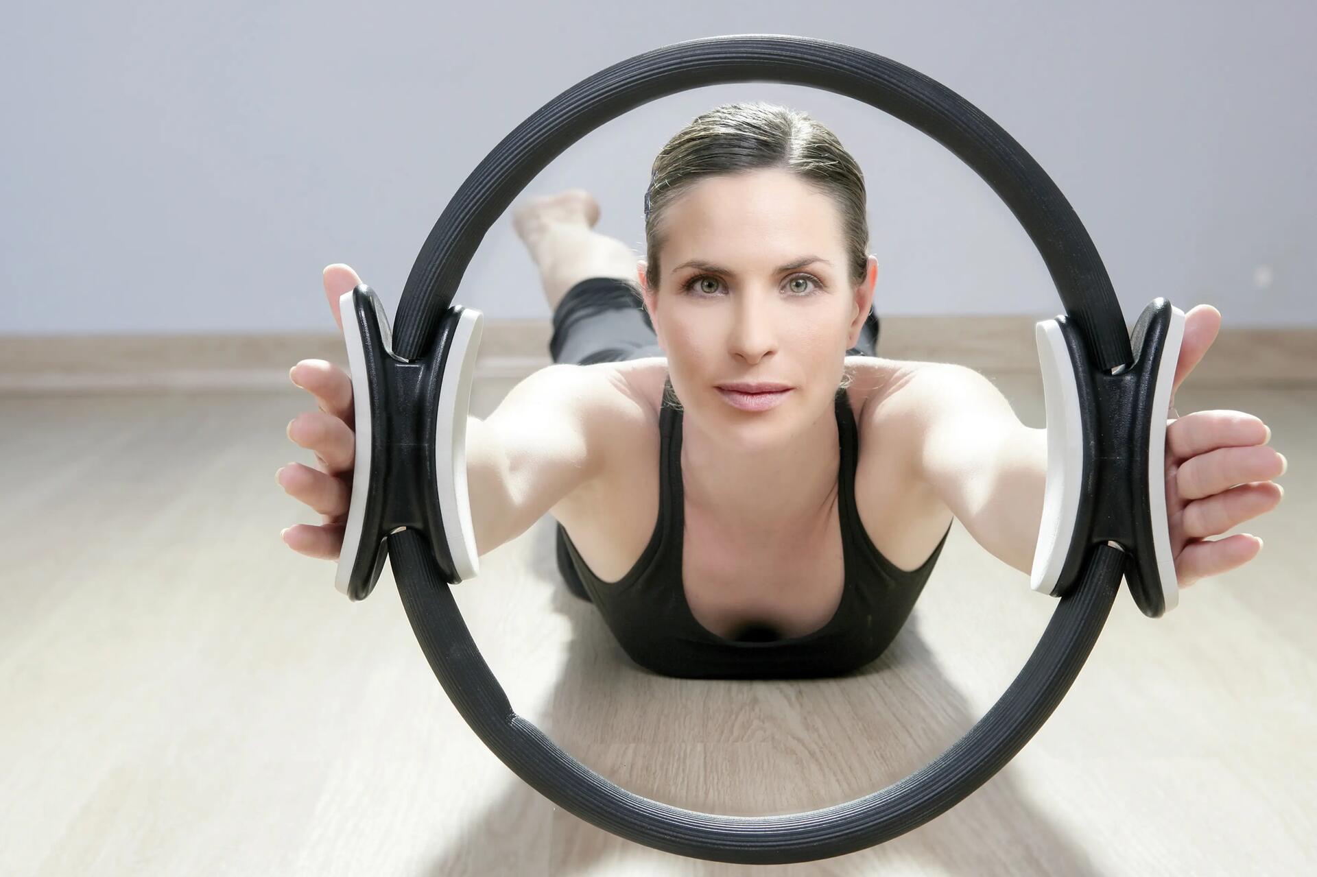 Kobieta leżąca na brzuchu na podłodze ćwicząca pilates z obręczą