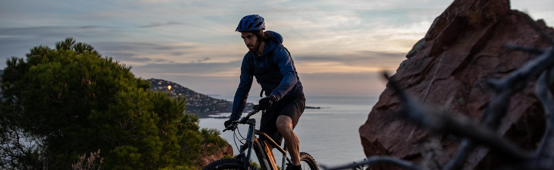 mężczyzna w kasku rowerowym jadący na rowerze MTB w górach