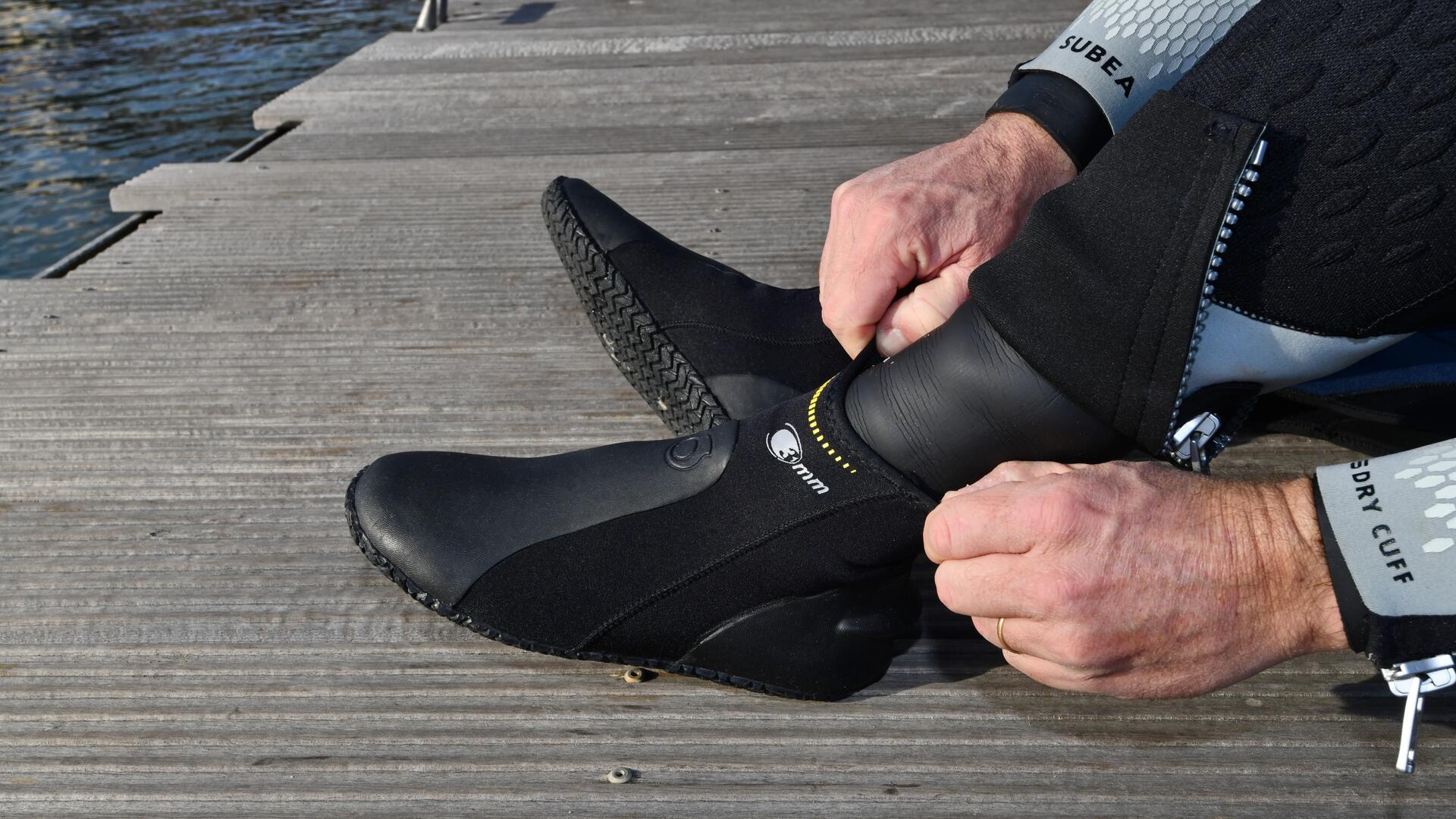 mężczyzna nakładające buty neoprenowe