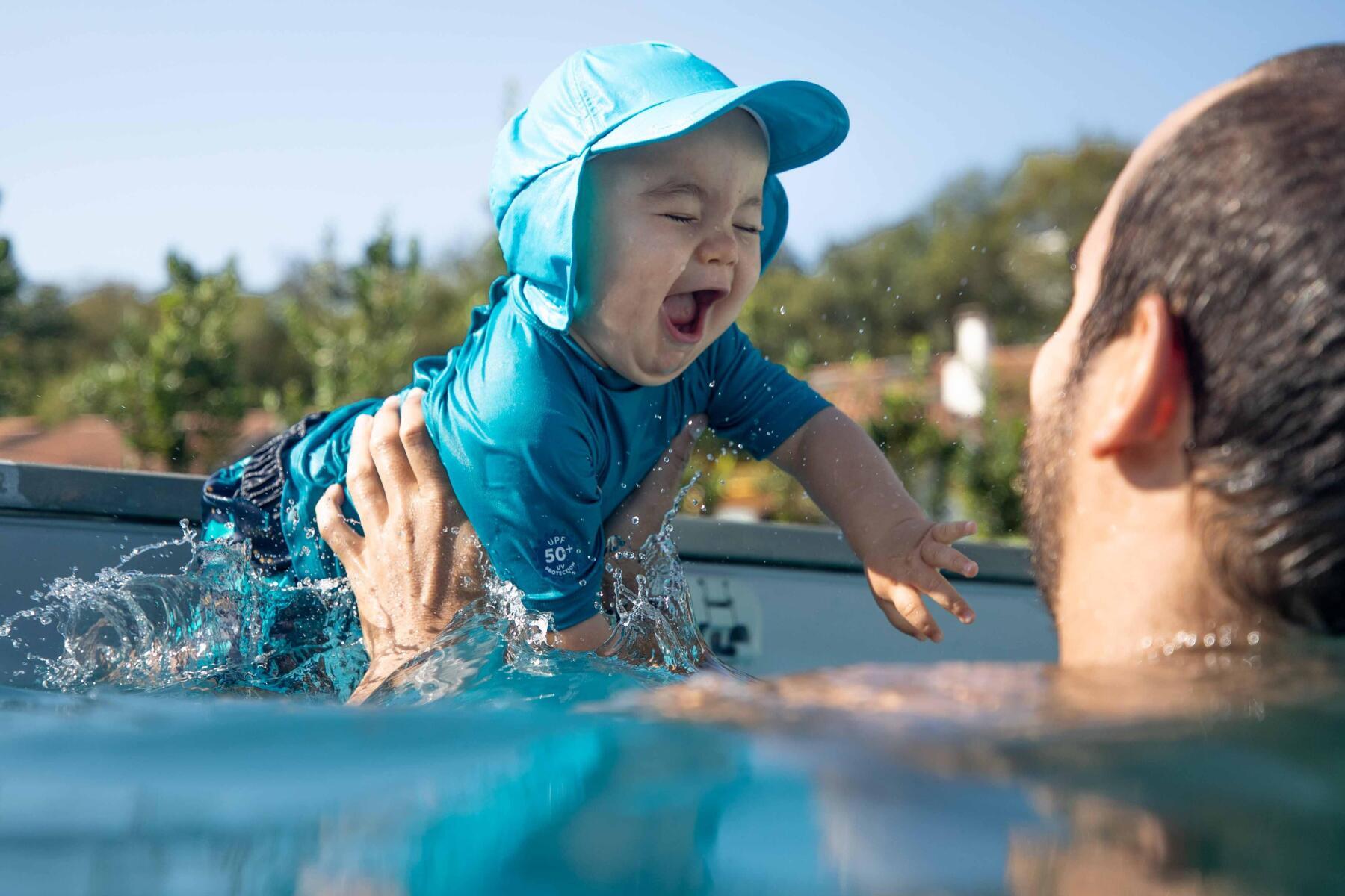 a kid jumps in water on daddy's arms