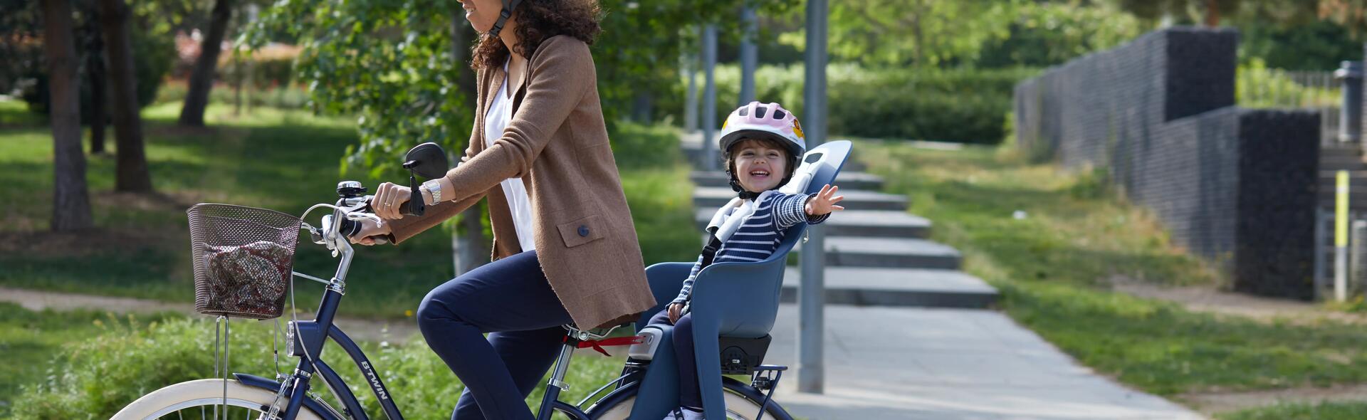 kobieta jadąca na rowerze z  dzieckiem foteliku rowerowym