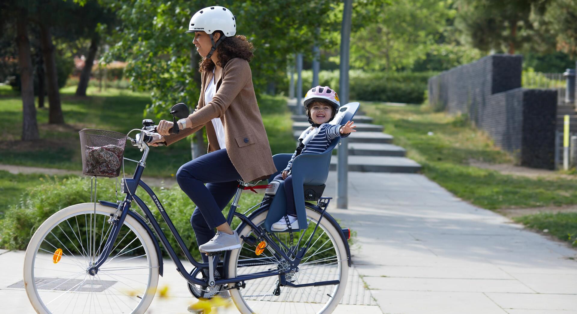 kobieta jadąca na rowerze z dzieckiem w foteliku rowerowym