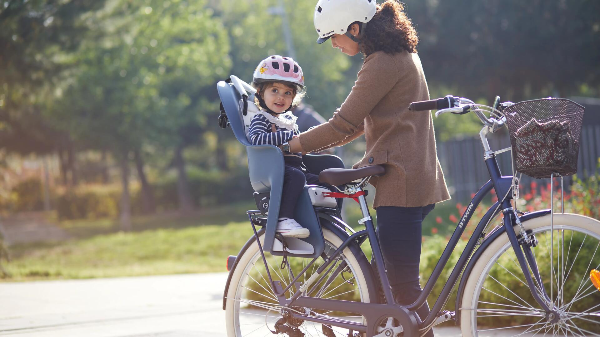 kobieta w kasku rowerowym wyciągająca dziecko z fotelika rowerowego