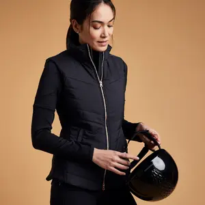 Mujer con un chaleco de equitación negro sujetando un casco