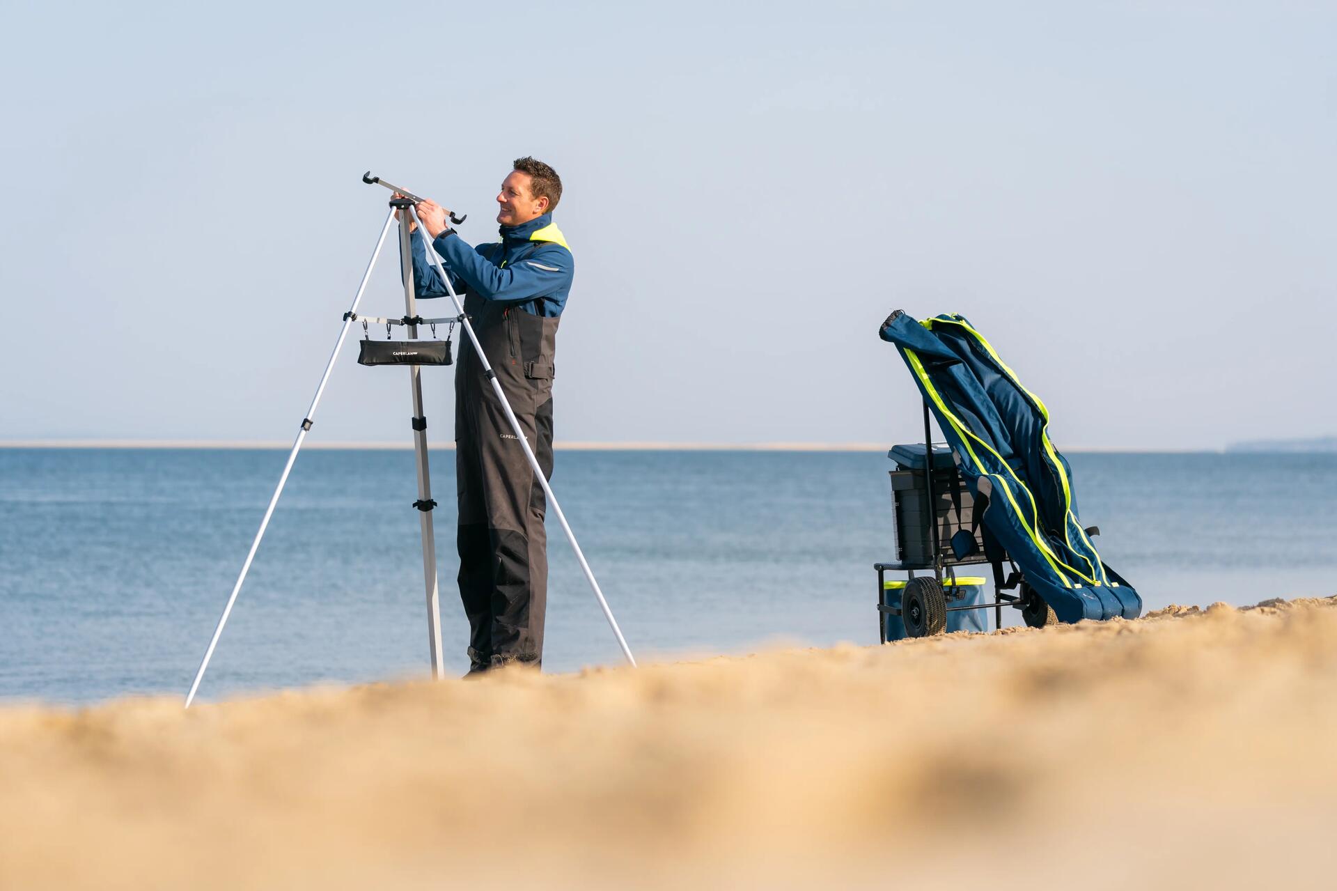 Mężczyzna rozstawiajacy statyw na plaży