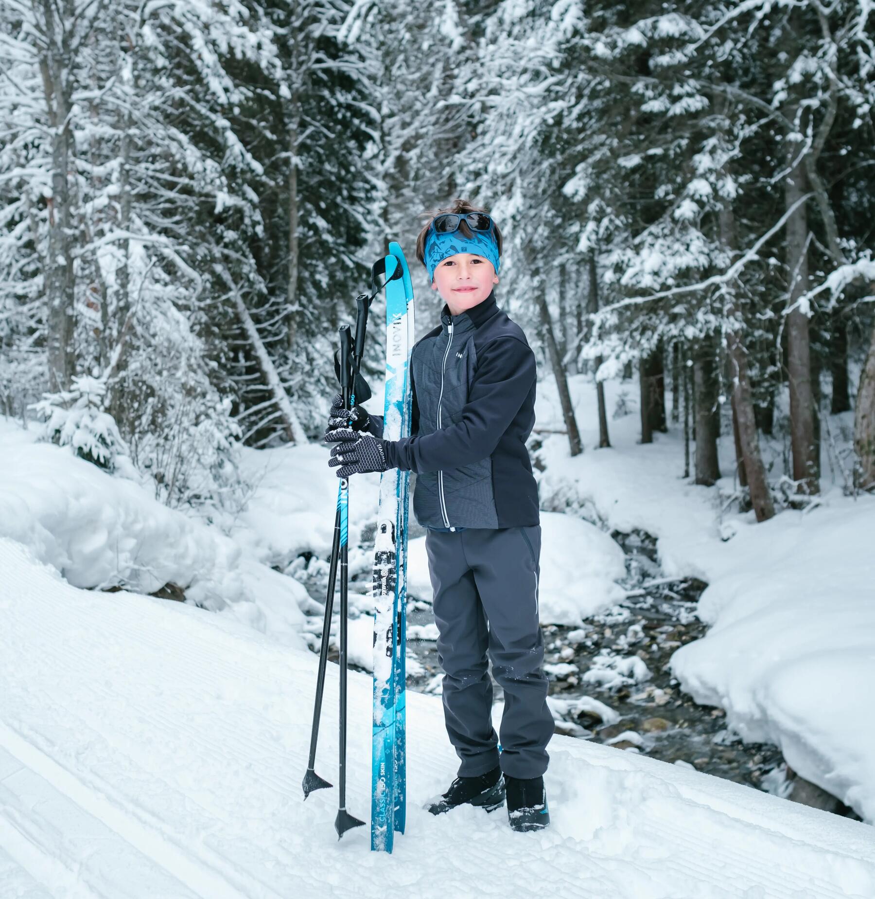 young boy holding cross-country skis and poles