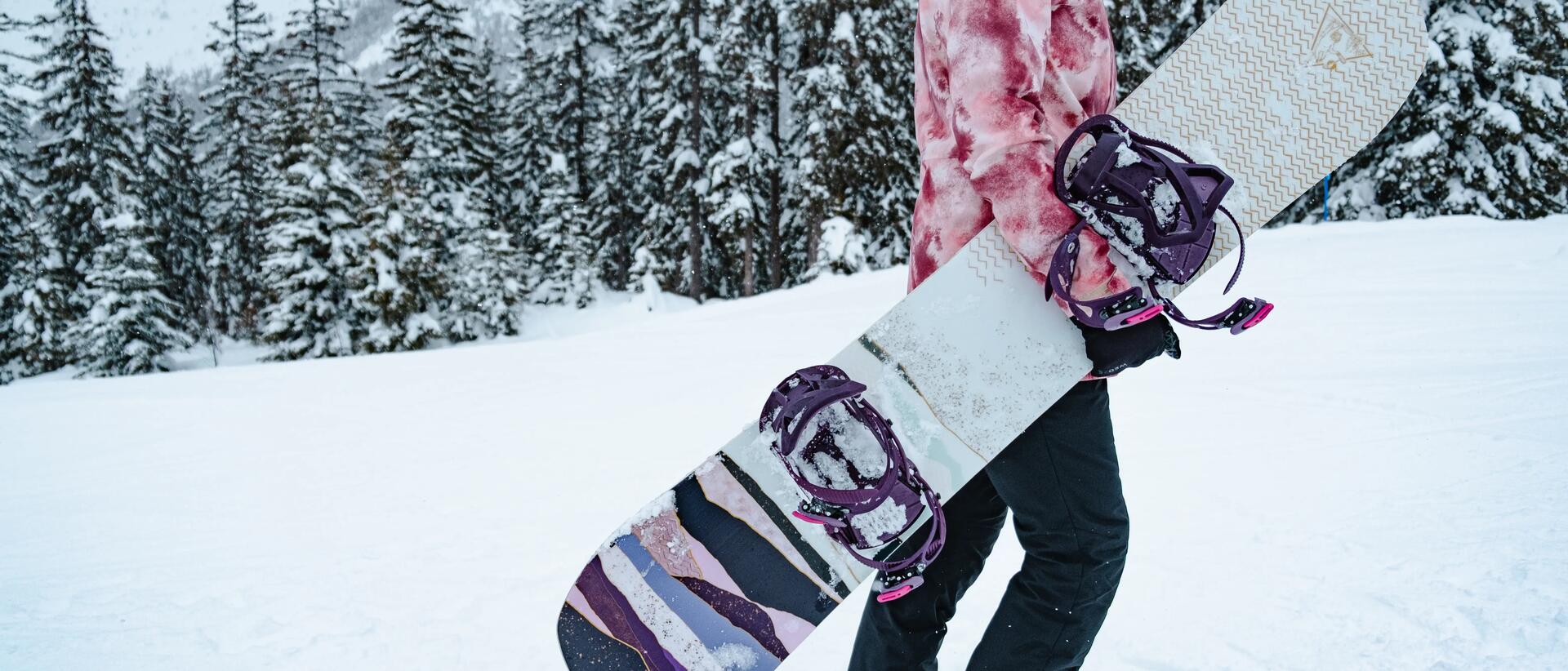 kobieta w stroju snowboardowym trzymająca deskę snowboardową