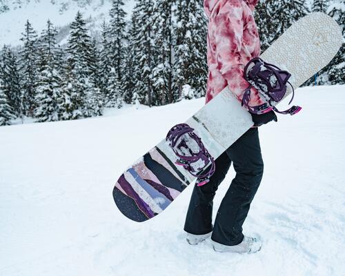 Woman carrying snowboard in snow