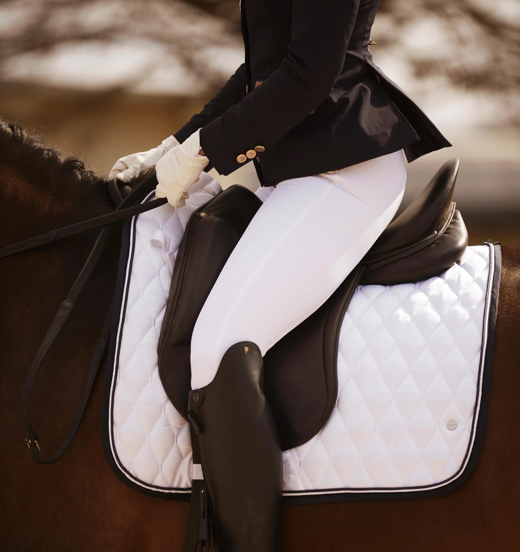 Cavalière de dressage bien assise dans sa selle avec des quartiers plus longs et avec les étriers chaussés longs