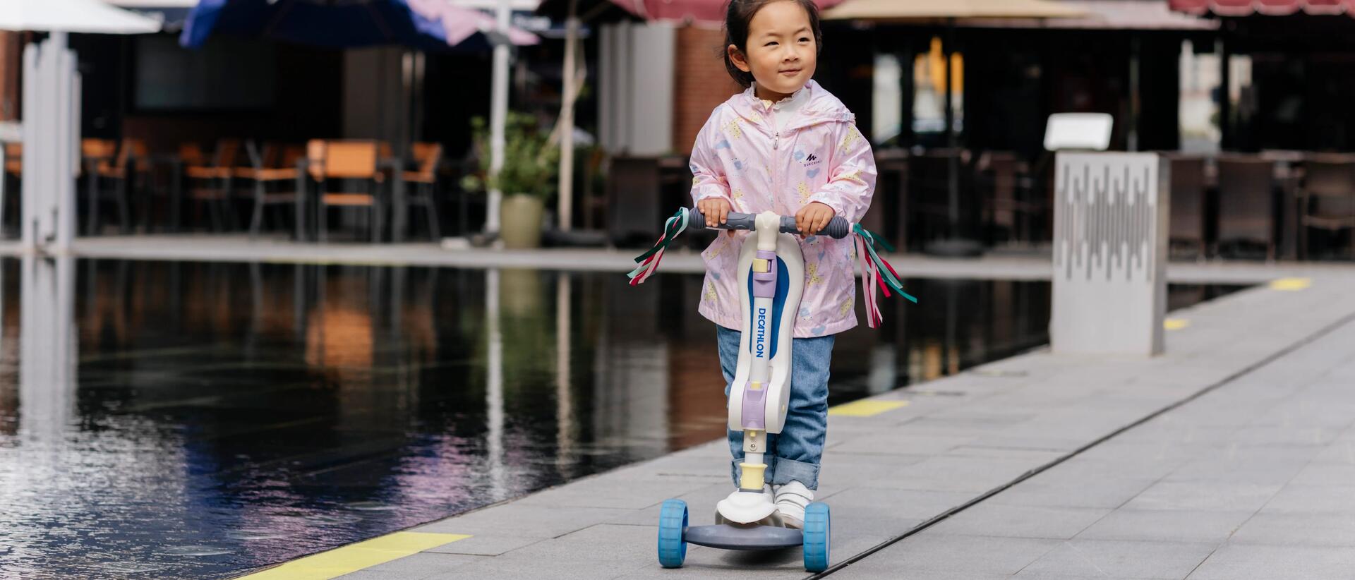 Young girl riding Decathlon Scooter outside.