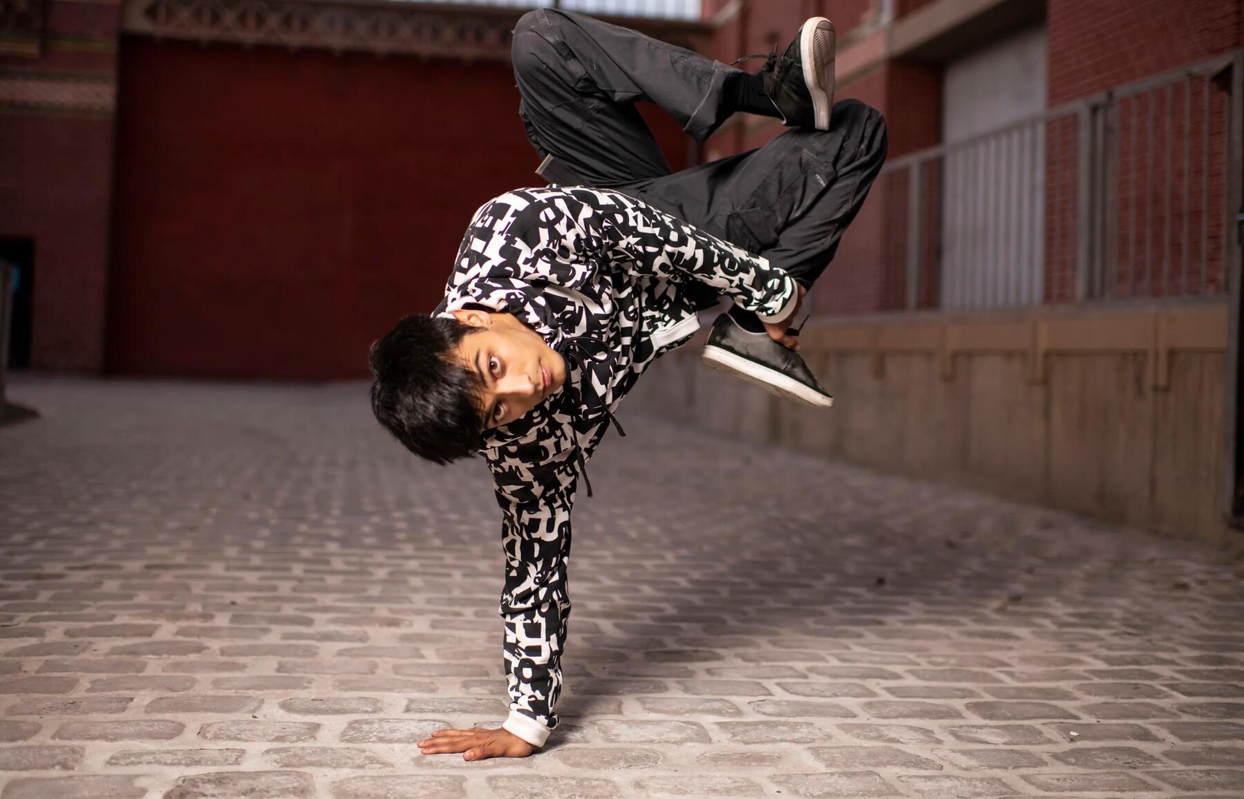 Un garçon qui présente un chorégraphie de danse dans une ruelle