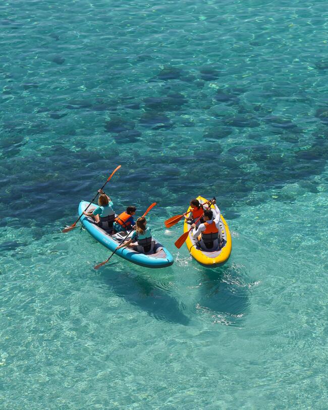 Zwei Kanus im türkisblauen Wasser. Menschen mit oranger Ausrüstung, paddelnd auf klarem Meer.