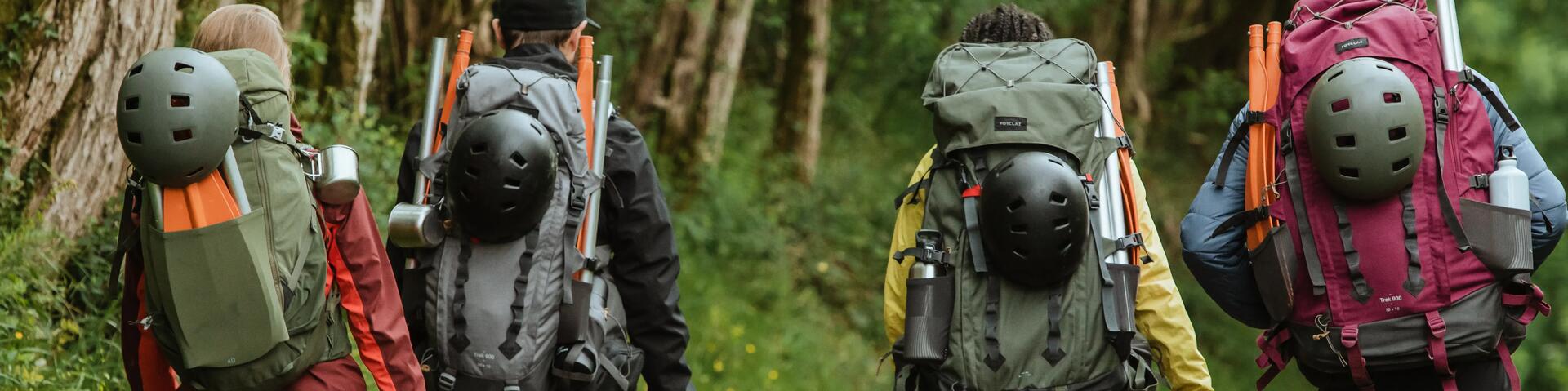 Four hikers wearing large backpacks while walking down a track.