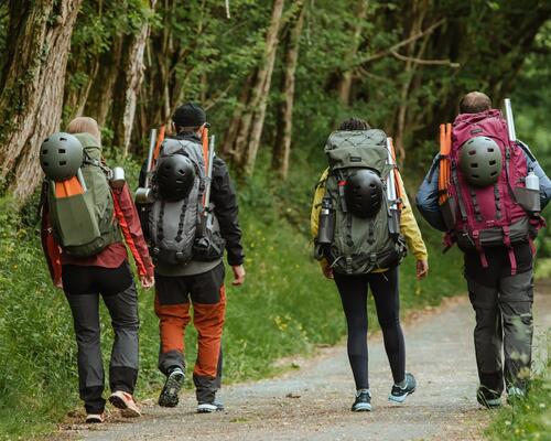 Four hikers wearing large backpacks while walking down a track.