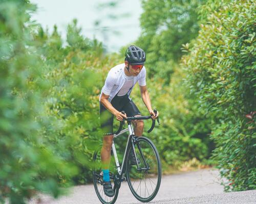Man cycling in greenery, wearing a black cycling cap.