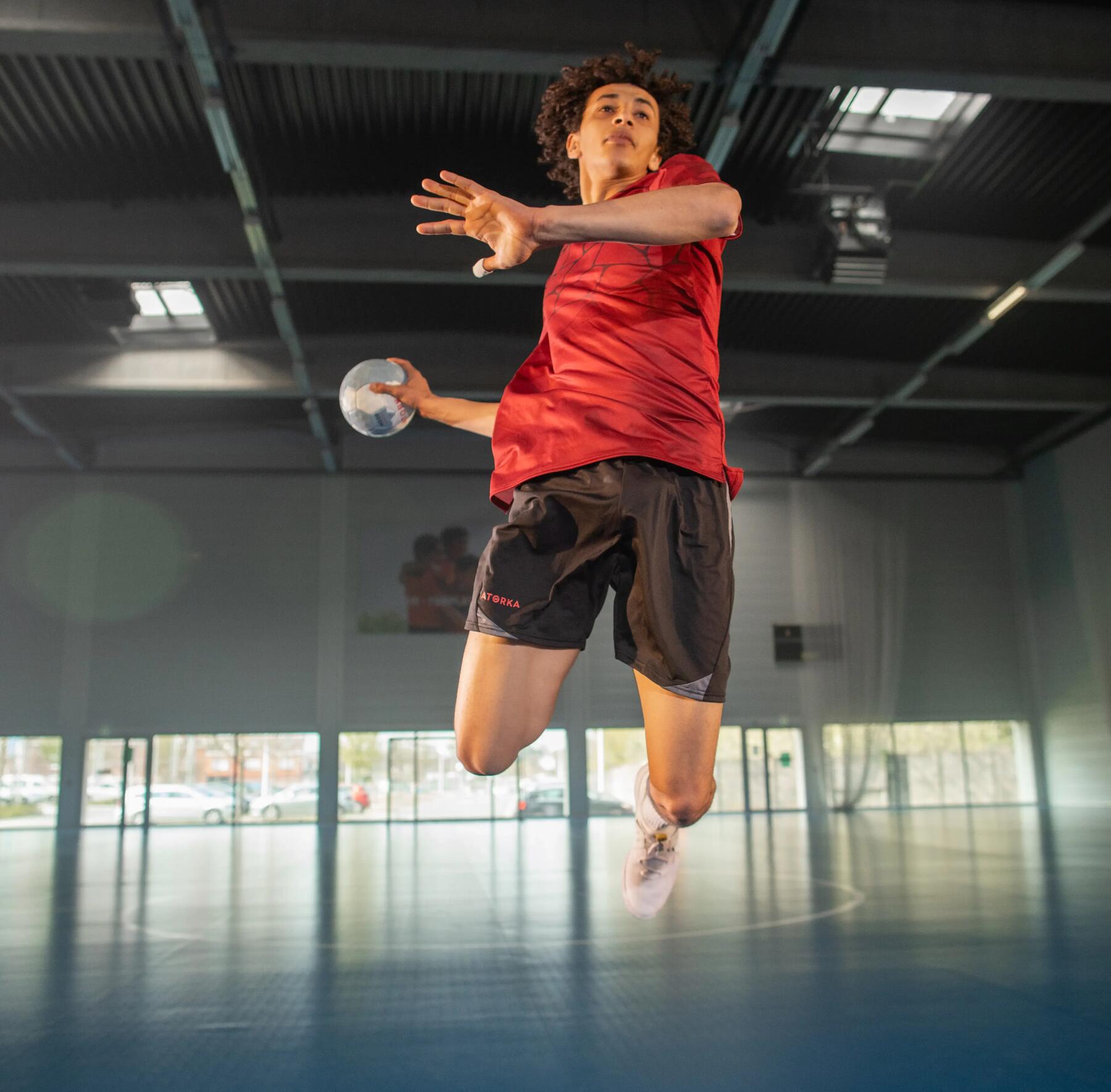 mężczyzna w odzieży do gry w piłkę ręczną skaczący z piłką ręczną w dłoni