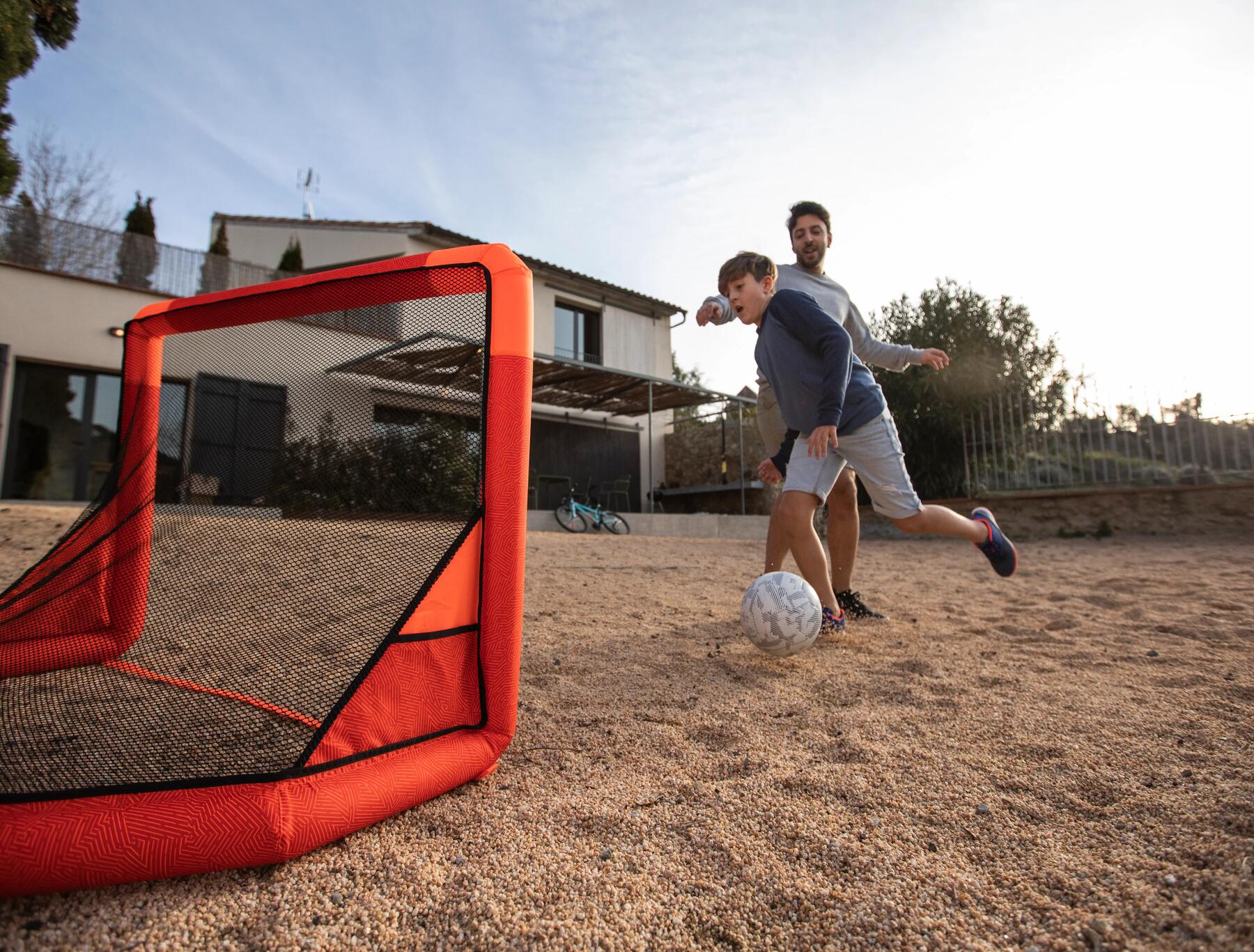 Two people playing with a portable goal on sand