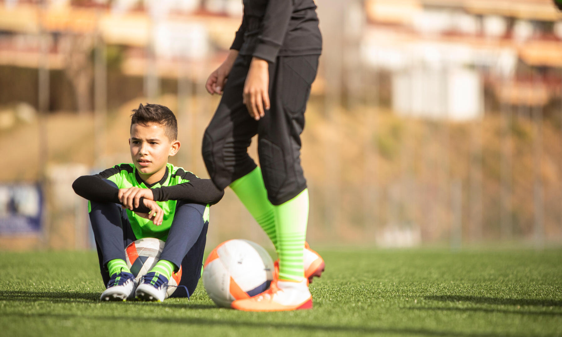 little boy sitting on the soccer field