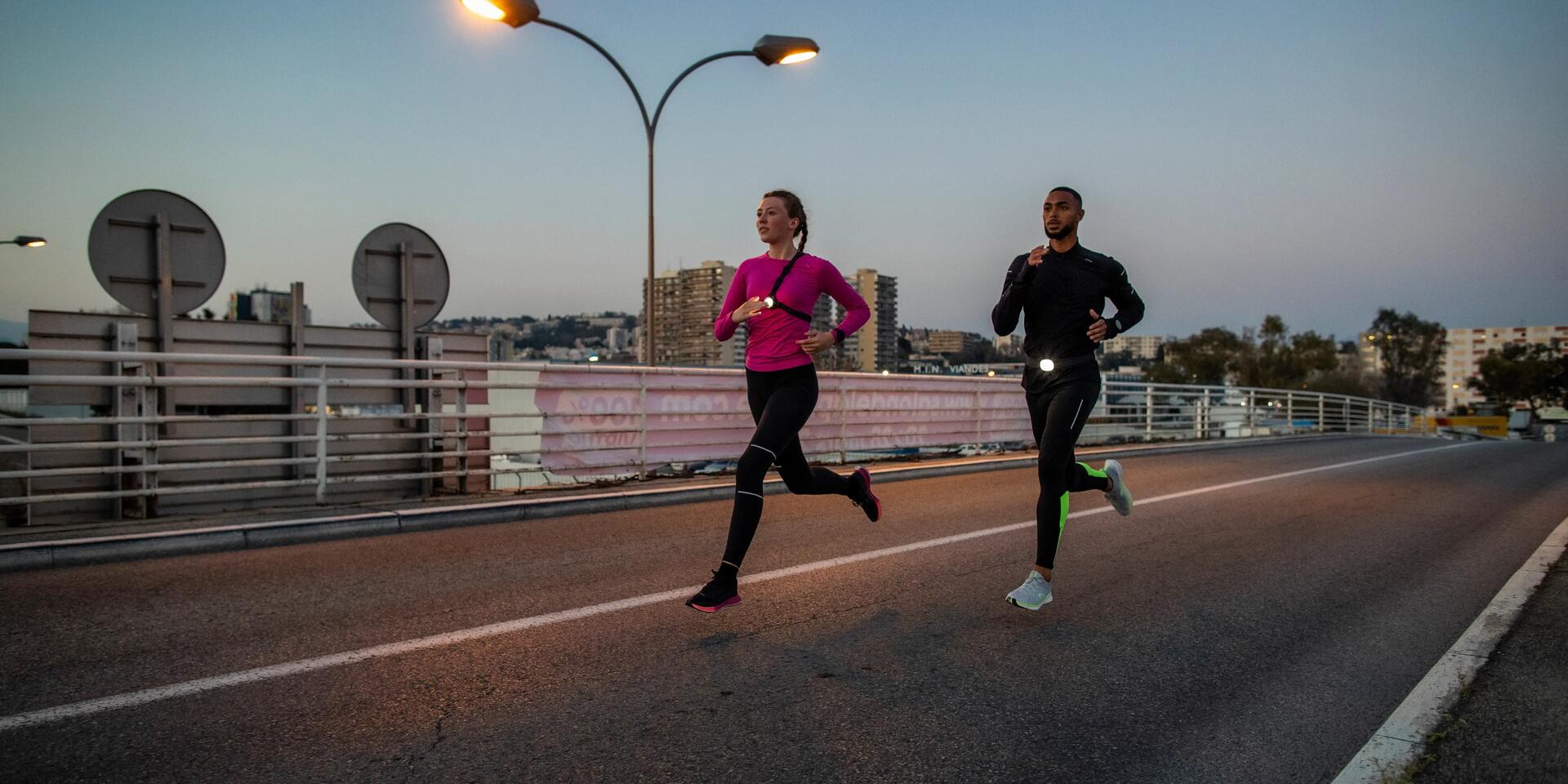 Para w strojach sportowych i odblaskach biegająca po mieście