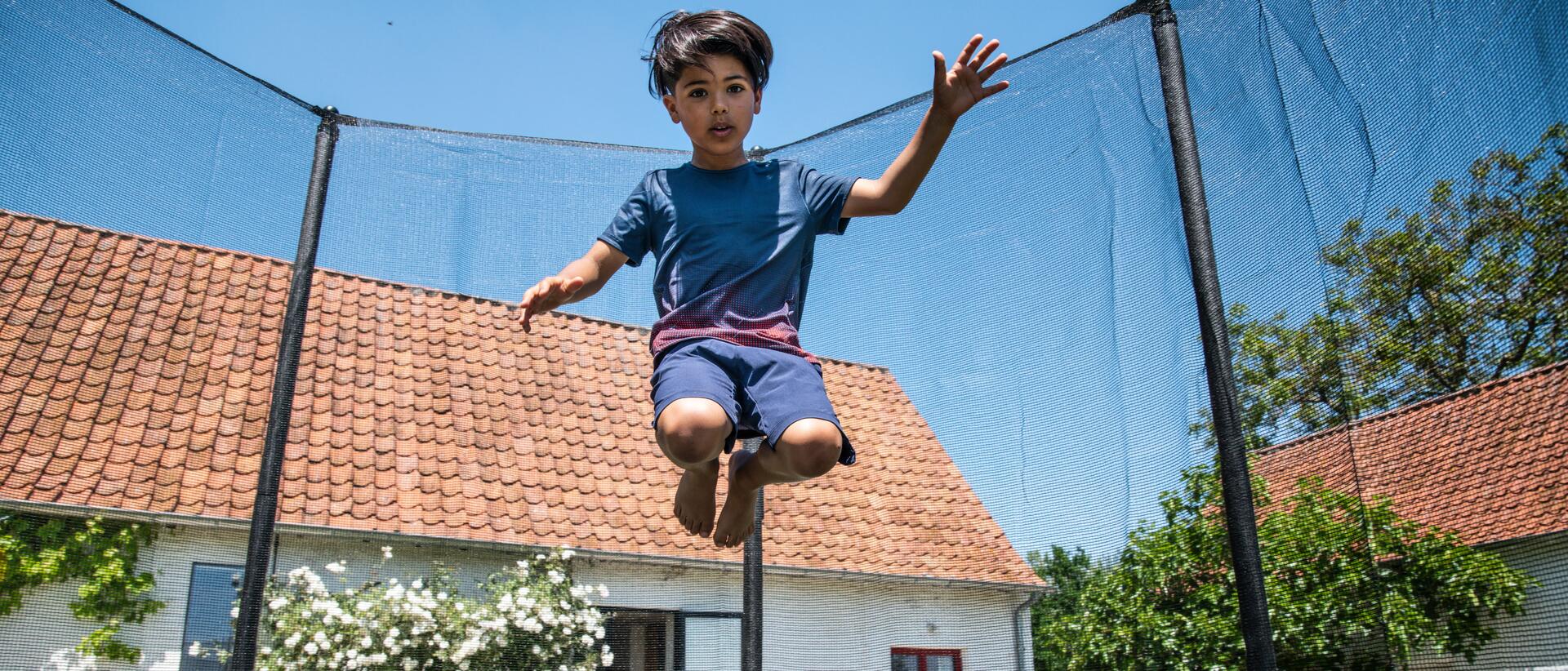 chłopiec skaczący na trampolinie ogrodowej